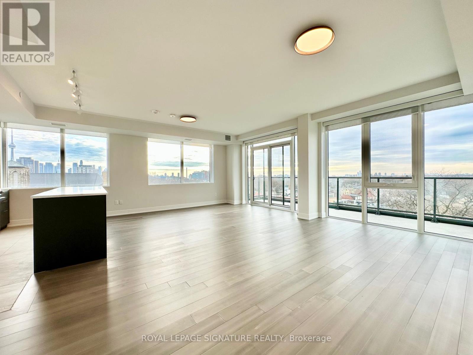 A spacious room with wooden floors and large windows overlooking a cityscape.