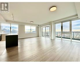 A spacious room with wooden floors and large windows overlooking a cityscape.