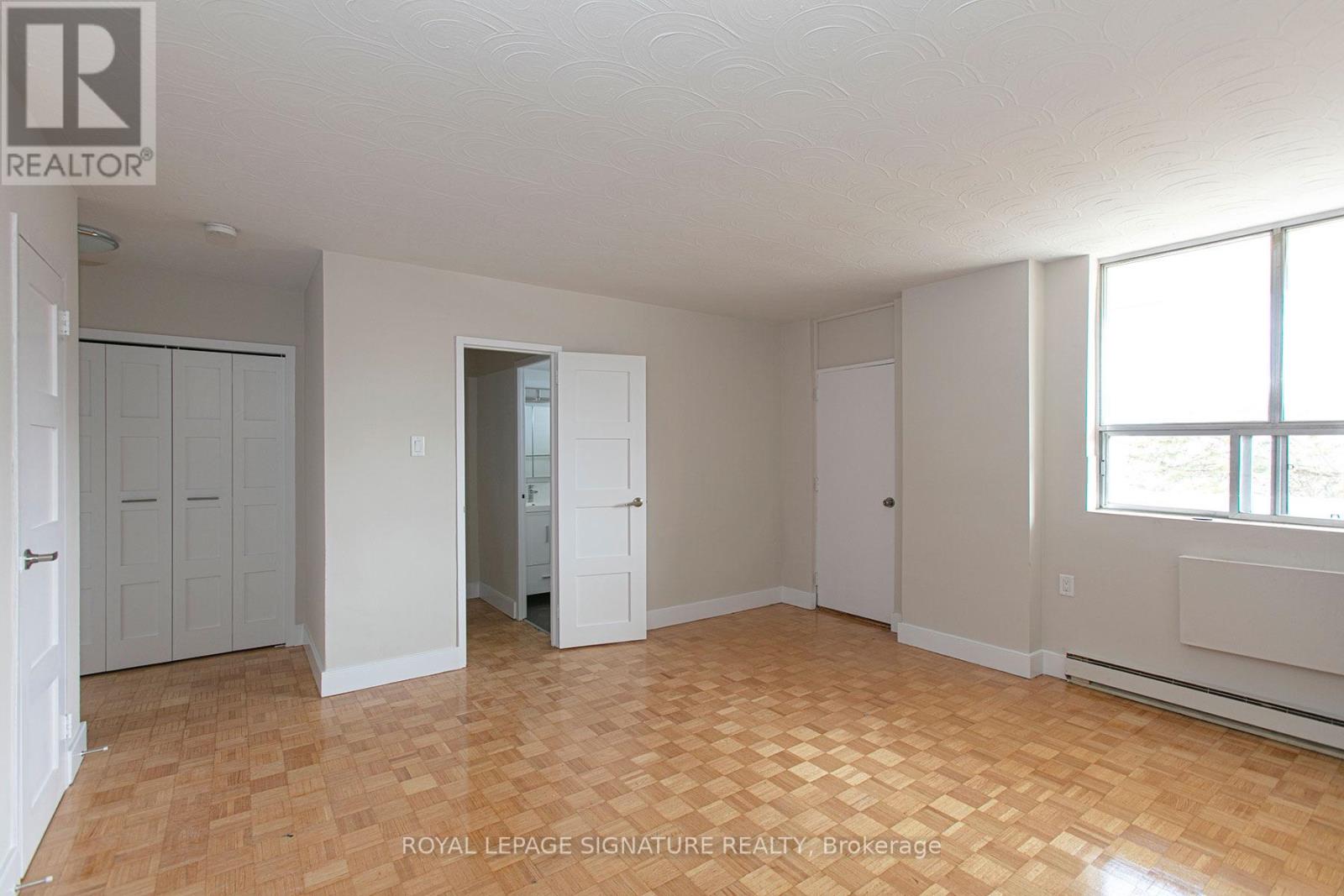 A room with wooden flooring and white walls, with a window on the right side.