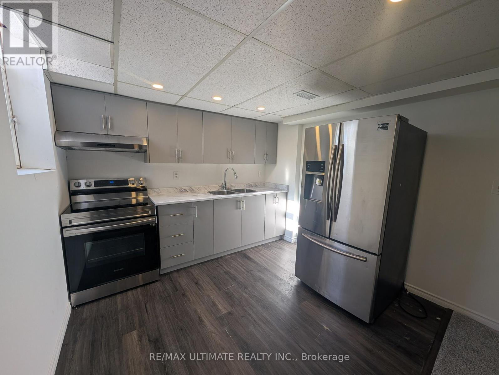A kitchen with a refrigerator, oven, and sink.