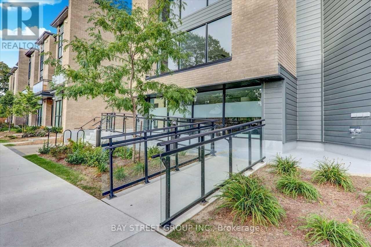 A modern building with a glass railing and a tree in front.