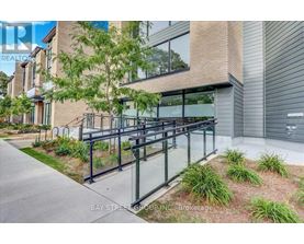 A modern building with a glass railing and a tree in front.