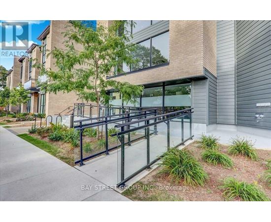 A modern building with a glass railing and a tree in front.
