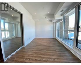 A spacious room with wooden flooring and large windows.
