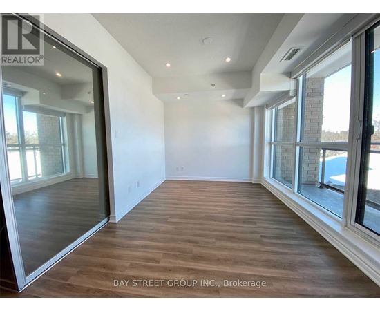 A spacious room with wooden flooring and large windows.