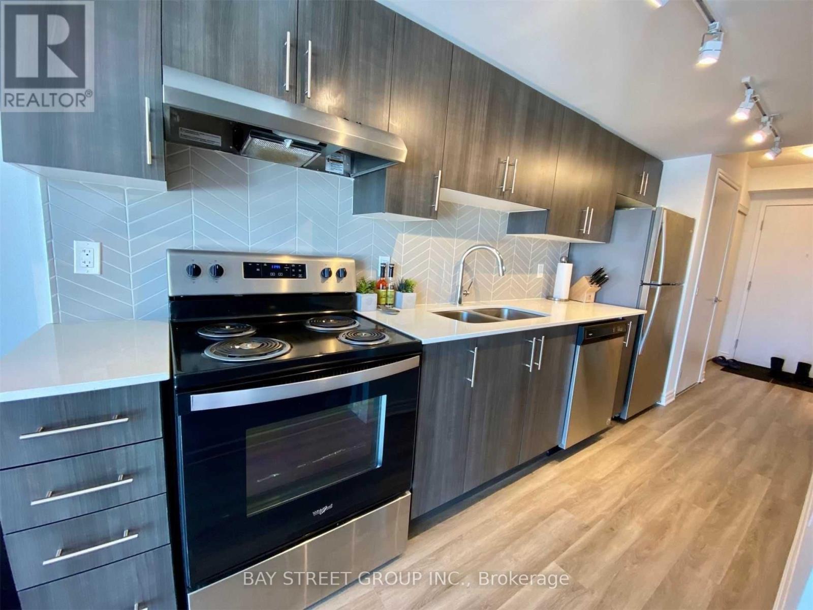 A modern kitchen with a stove top oven and a refrigerator.