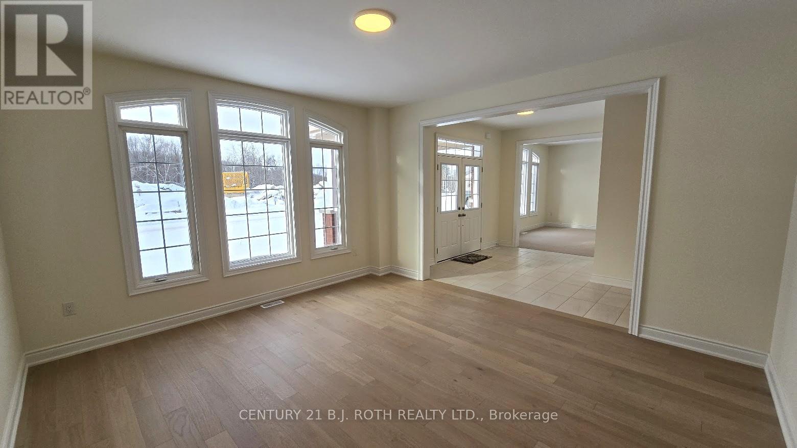 A spacious room with wooden floors and large windows.