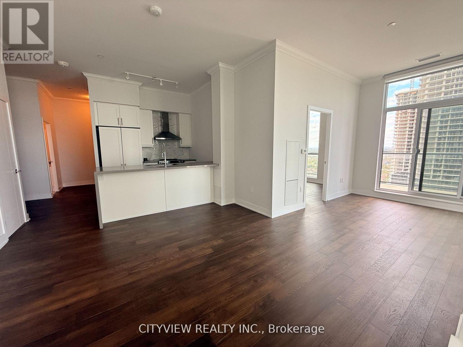 A spacious room with wooden flooring and white walls.