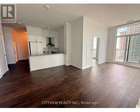 A spacious room with wooden flooring and white walls.