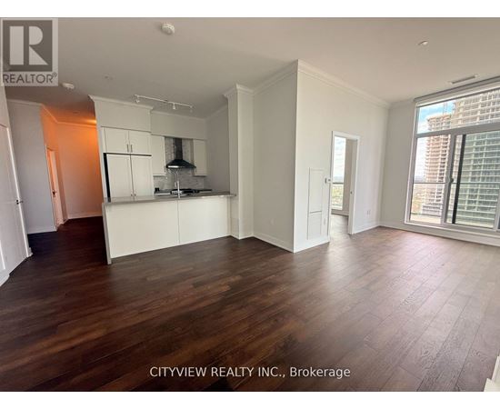 A spacious room with wooden flooring and white walls.