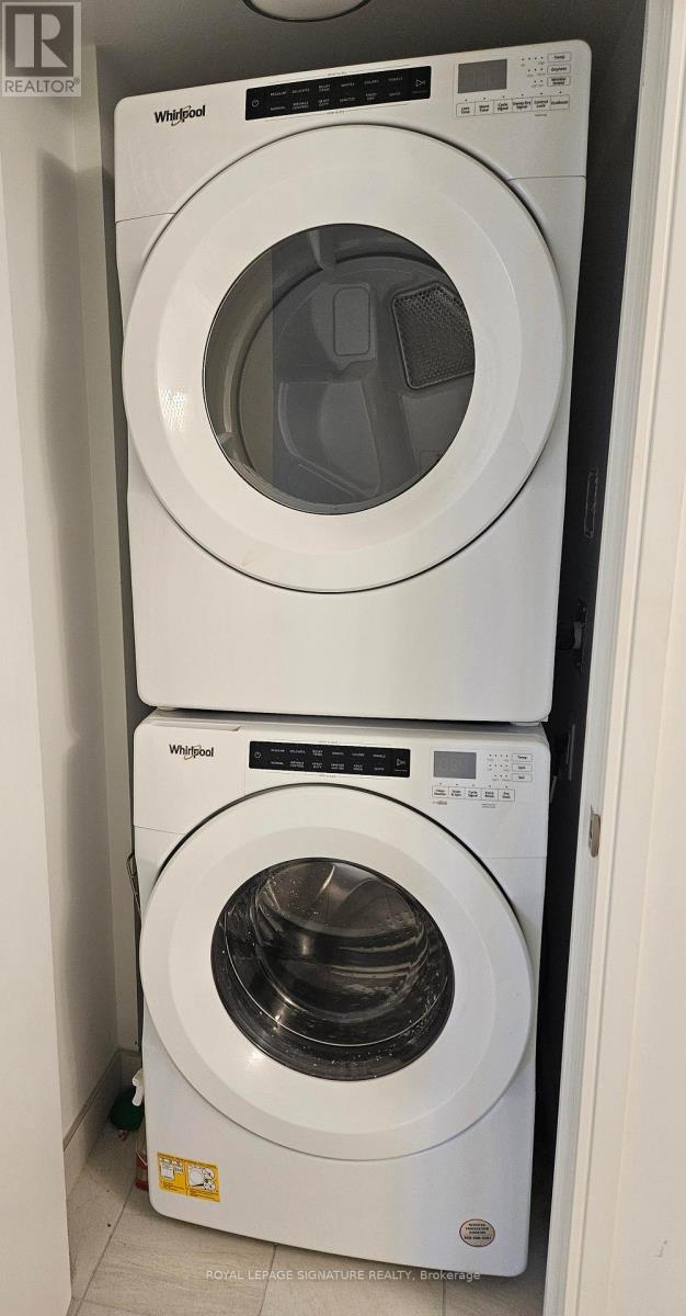 Two white Whirlpool washing machines stacked on top of each other.