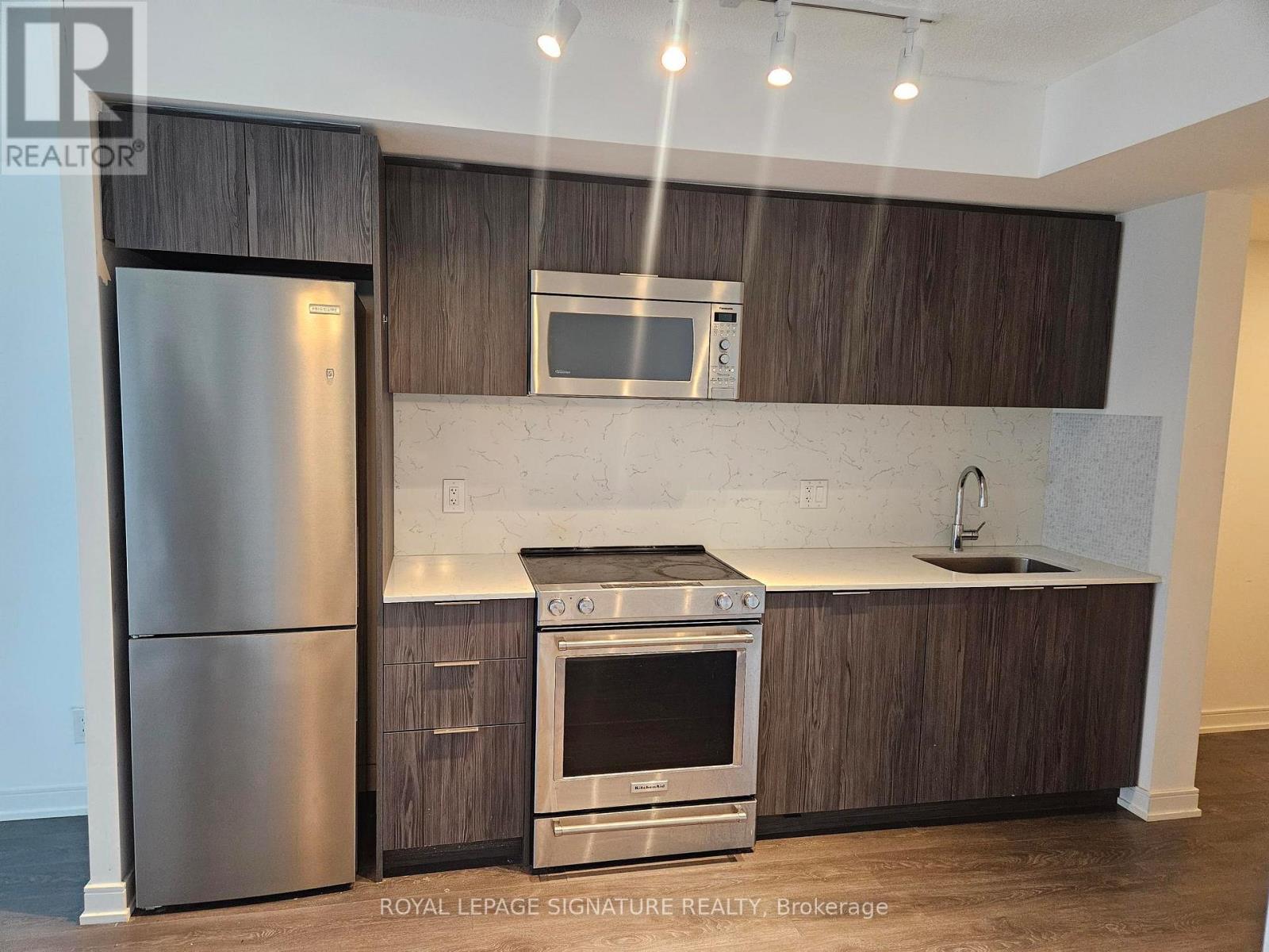 A modern kitchen with a stainless steel refrigerator and oven.
