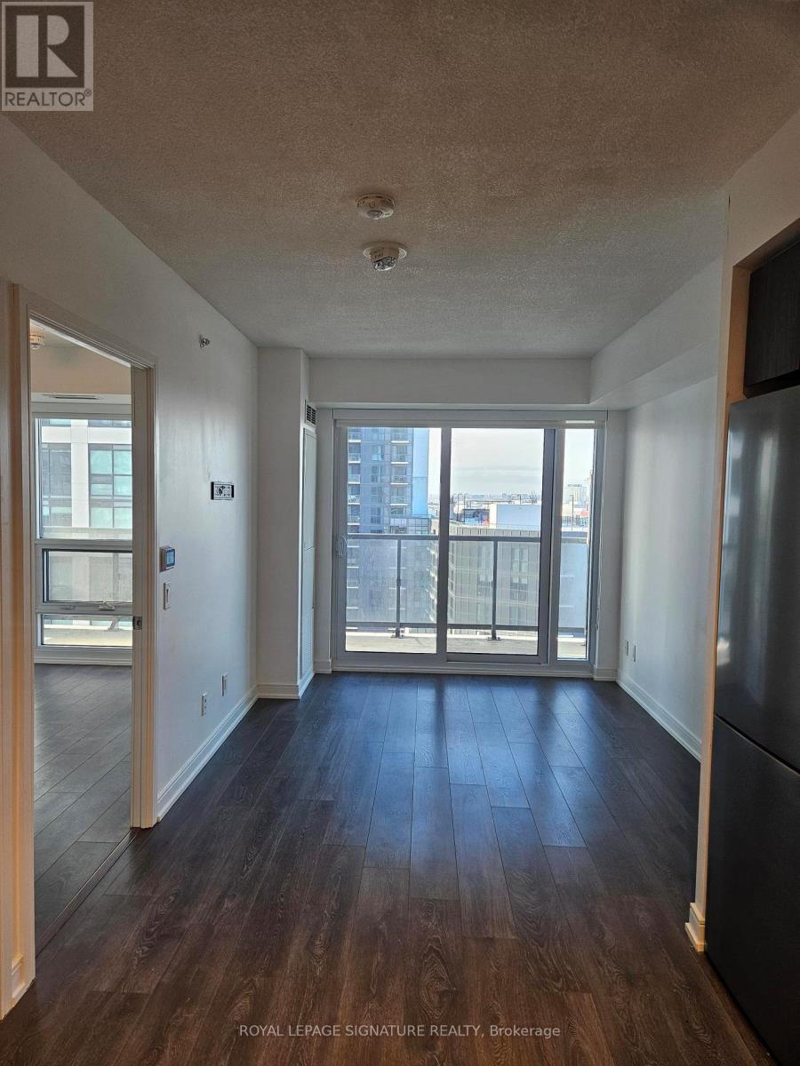 A spacious room with wooden floors and a balcony with a view of the city.