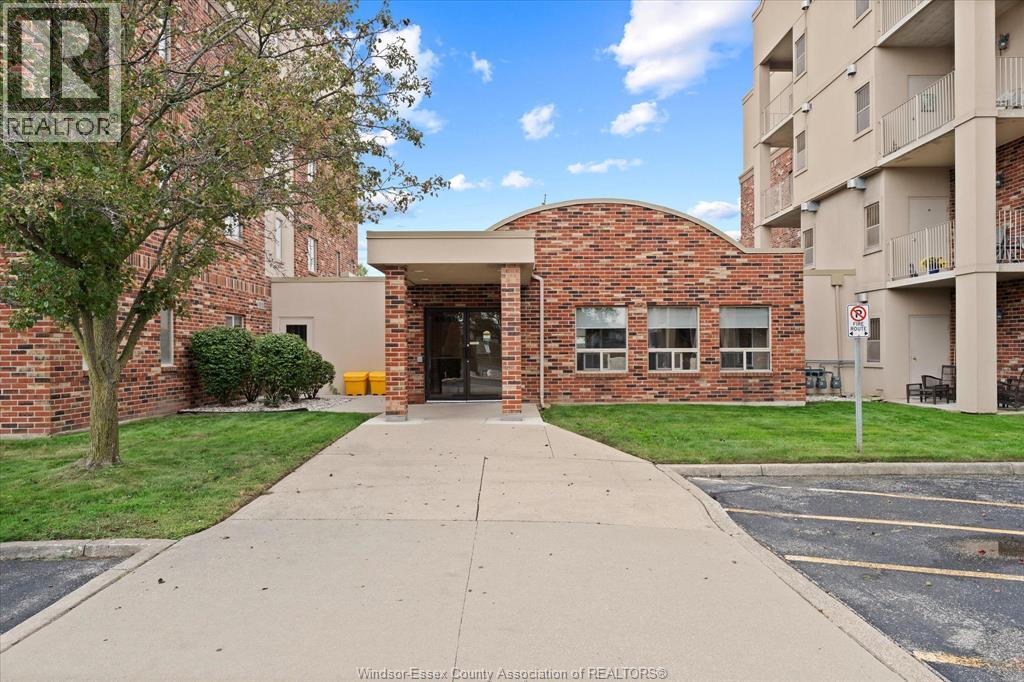 A brick building with a glass door and windows is in front of a parking lot.