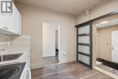 A kitchen with a sink and a black fridge.