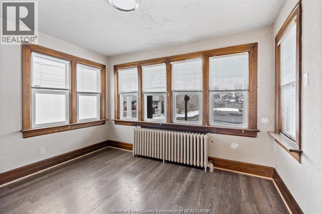 A room with wooden floors and a large window with a view of the street.