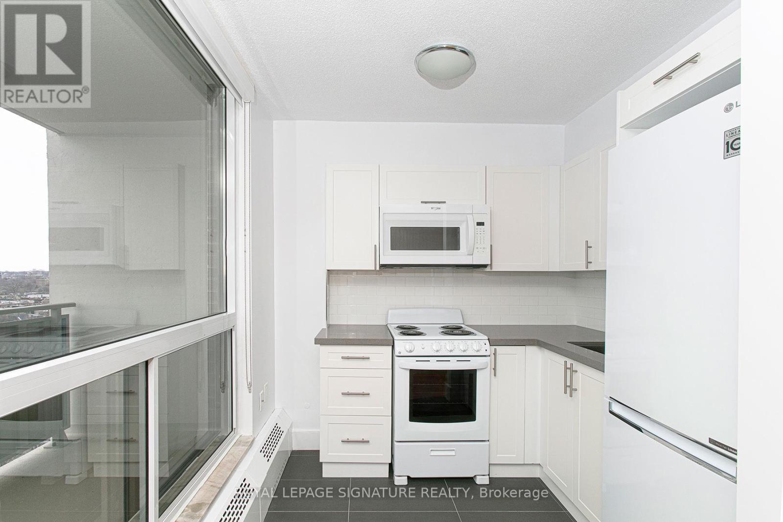 A small white kitchen with a microwave and stove.