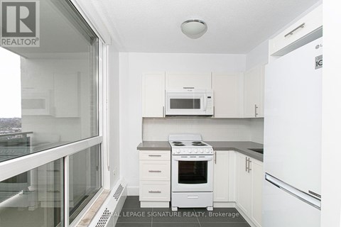 A small white kitchen with a microwave and stove.