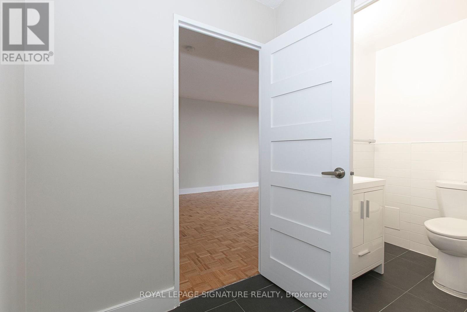 A white door is open to a bathroom with a toilet.