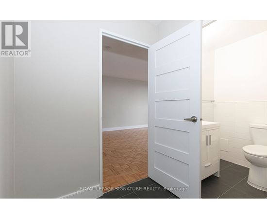 A white door is open to a bathroom with a toilet.