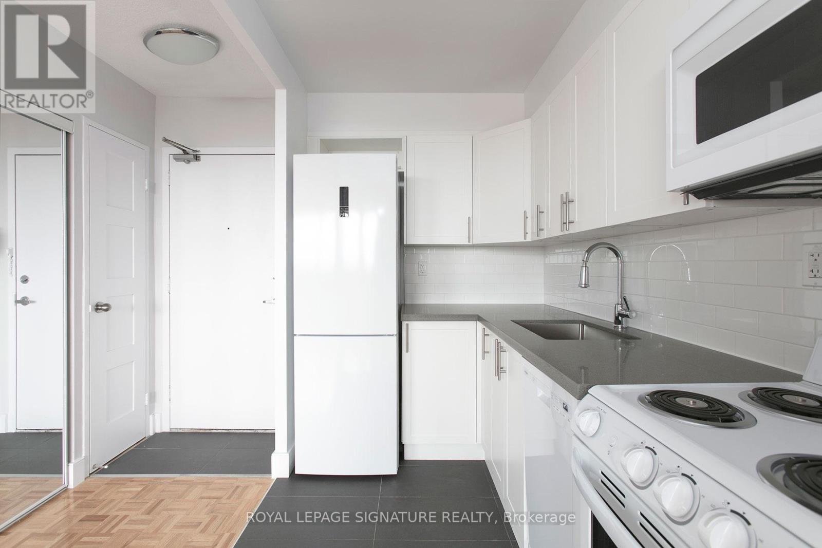 A white fridge in a kitchen with a white door and white cabinets.