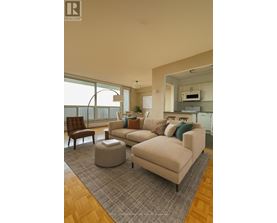 A living room with a couch, chair, ottoman, and a window.