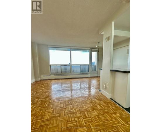 A room with wooden flooring and a large window.