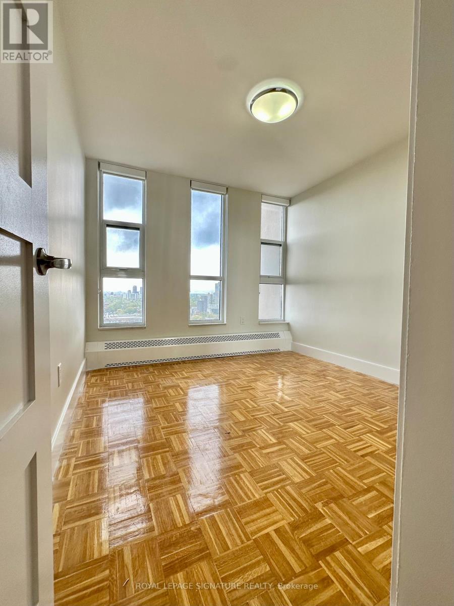 A room with wooden flooring and a window with a view of a city.