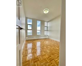 A room with wooden flooring and a window with a view of a city.