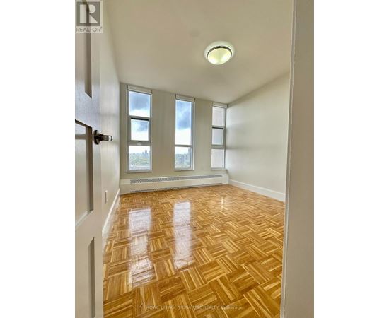 A room with wooden flooring and a window with a view of a city.