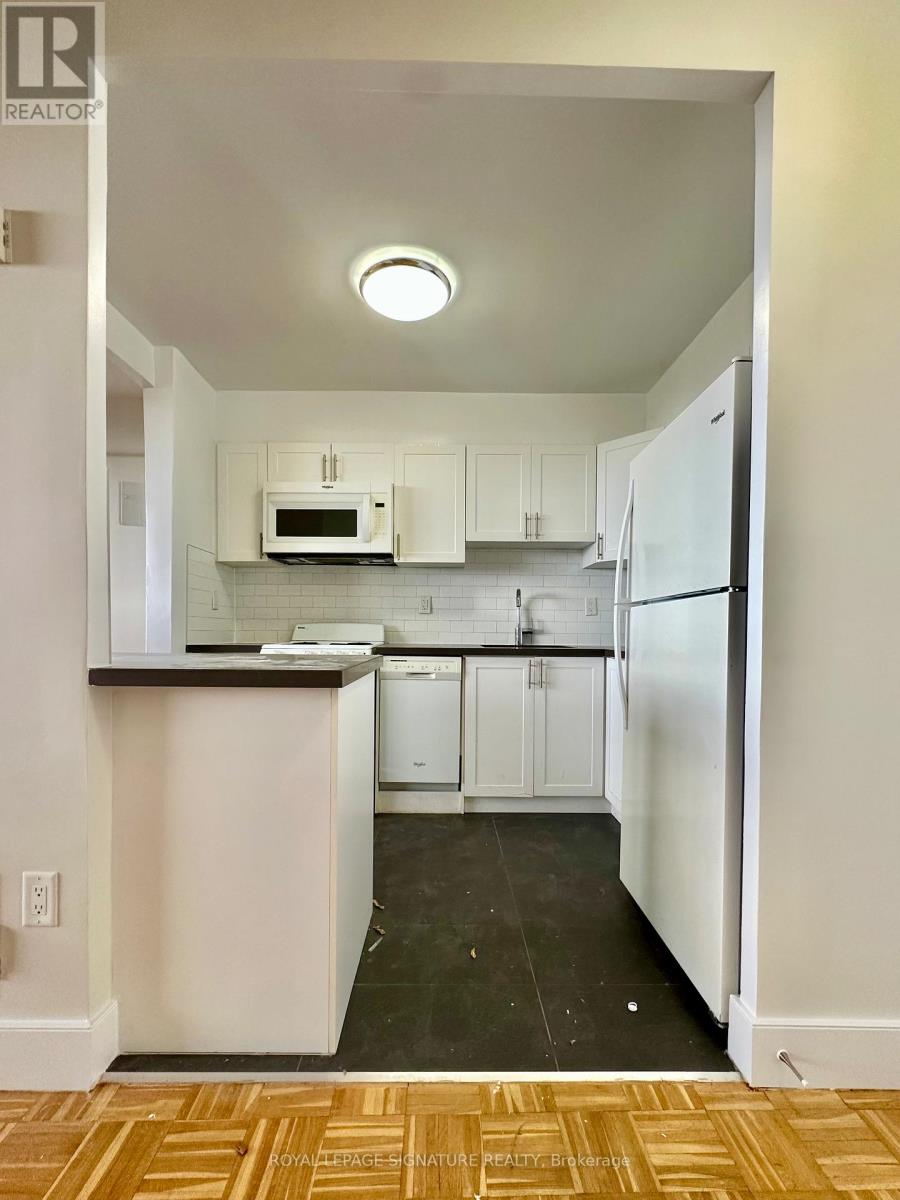 A kitchen with white cabinets and appliances.