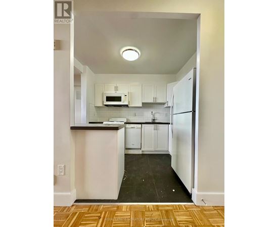 A kitchen with white cabinets and appliances.