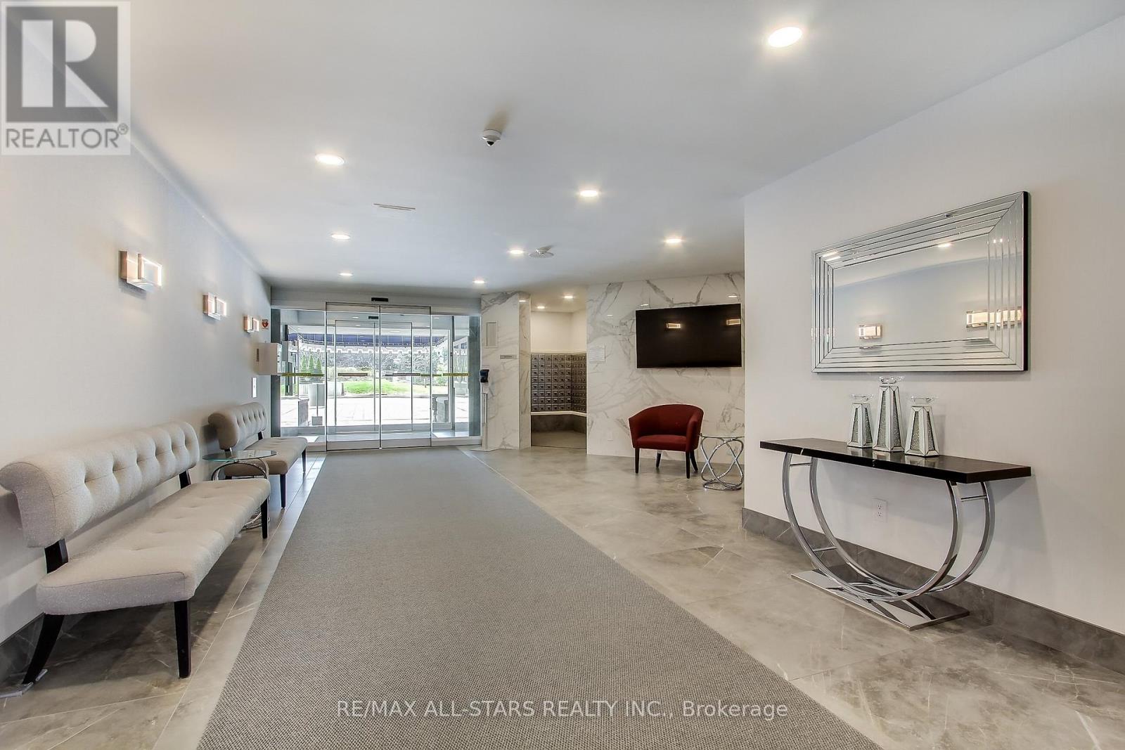 A spacious office lobby with a reception desk and a row of comfortable chairs.