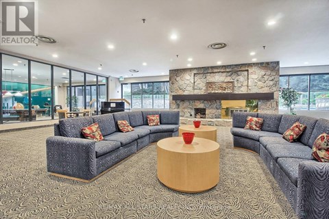 A living room with grey couches and a stone fireplace.
