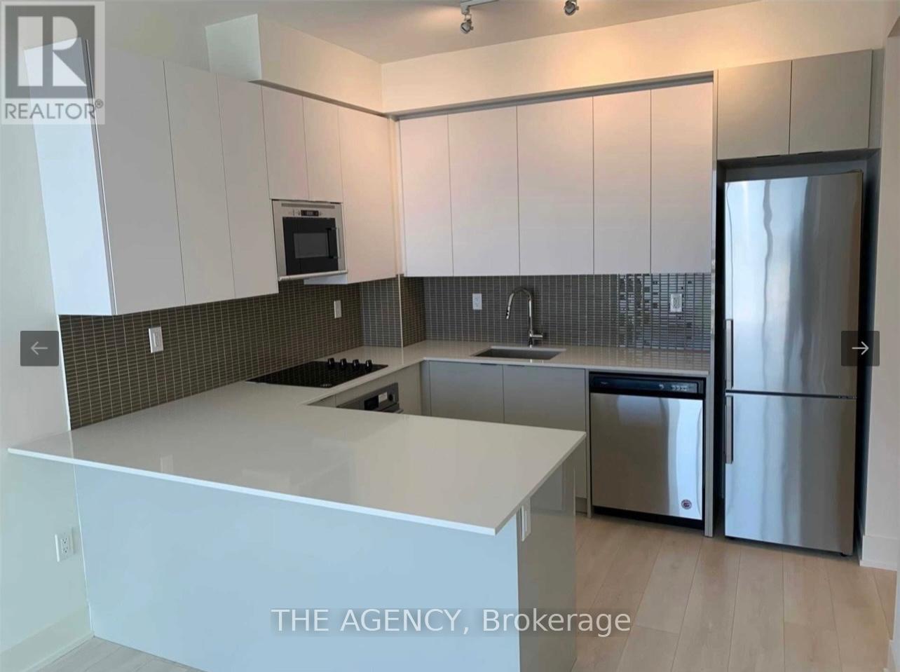 A modern kitchen with a refrigerator, microwave, and oven.