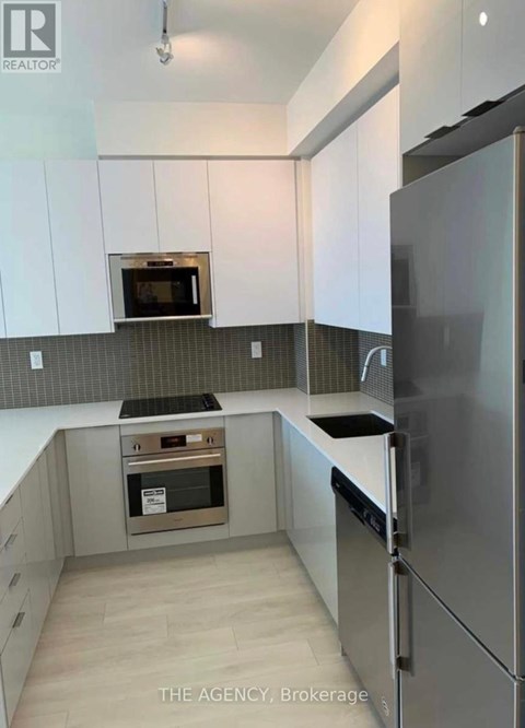 A kitchen with white cabinets and a stainless steel refrigerator.