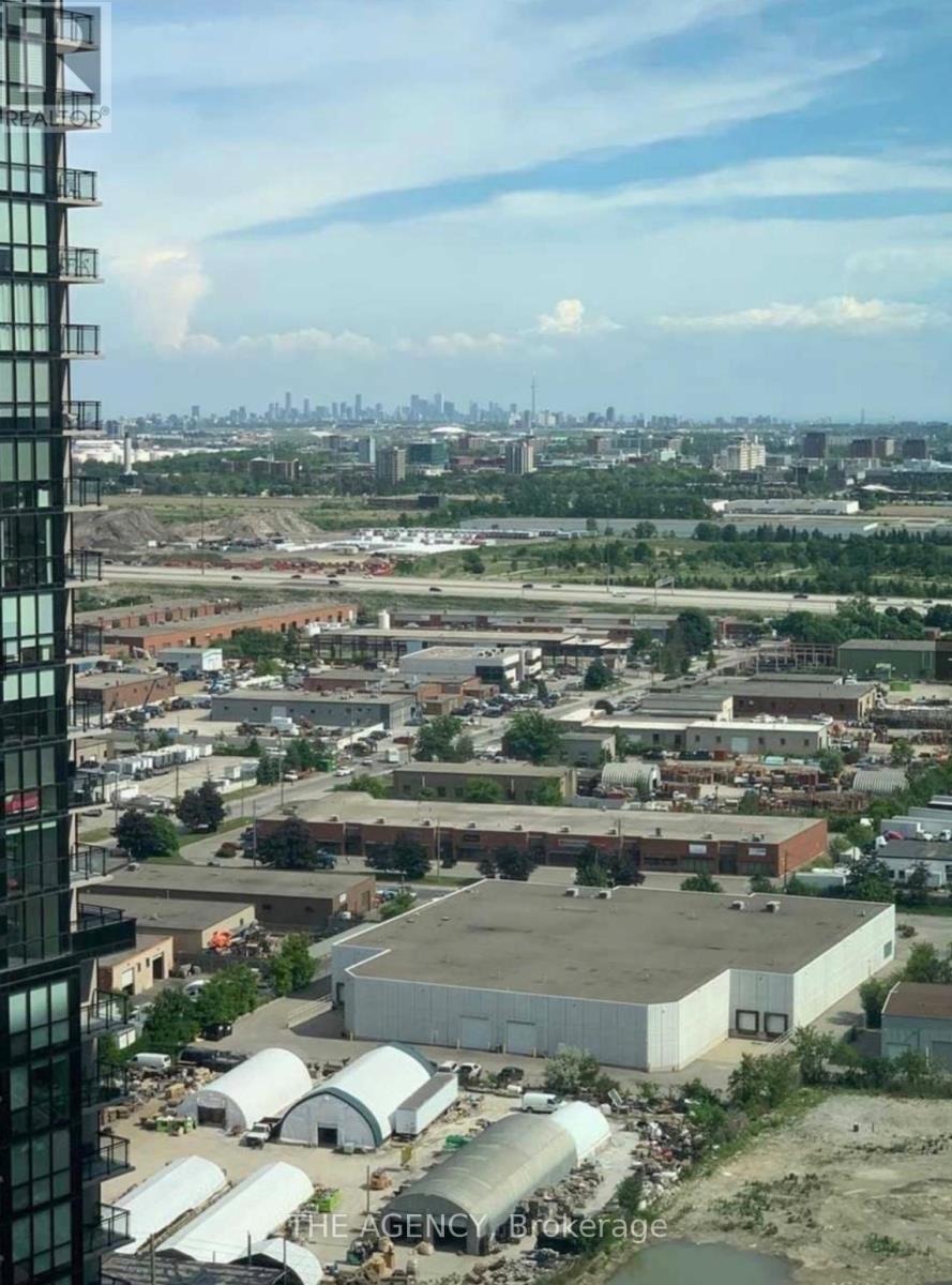 A view from a high-rise building looking down at a large industrial area with a city skyline in the distance.