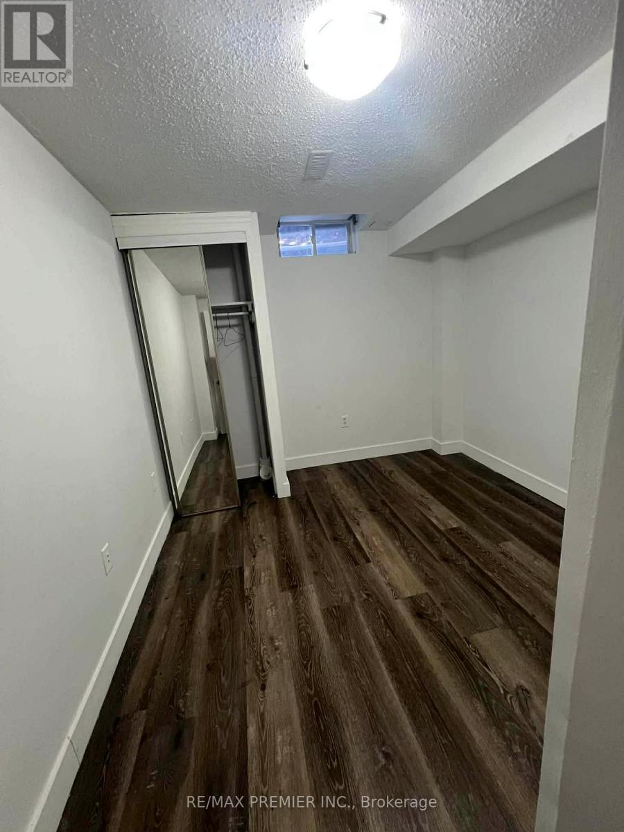 A room with wood flooring and a white wall with a doorway leading to another room.