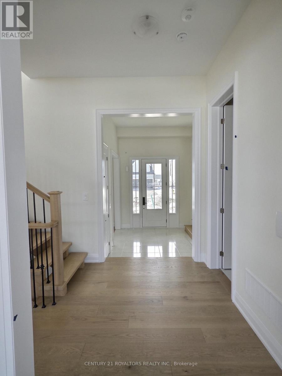 A long hallway with a staircase on the left and a door on the right.