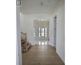 A long hallway with a staircase on the left and a door on the right.