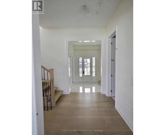 A long hallway with a staircase on the left and a door on the right.