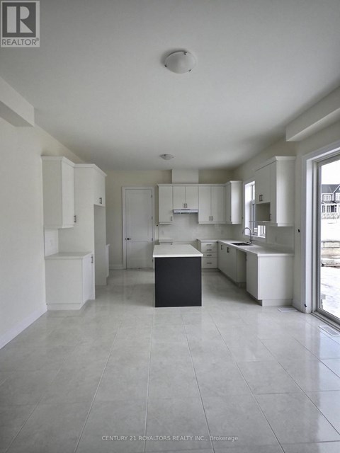 A spacious kitchen with white cabinets and a black island.