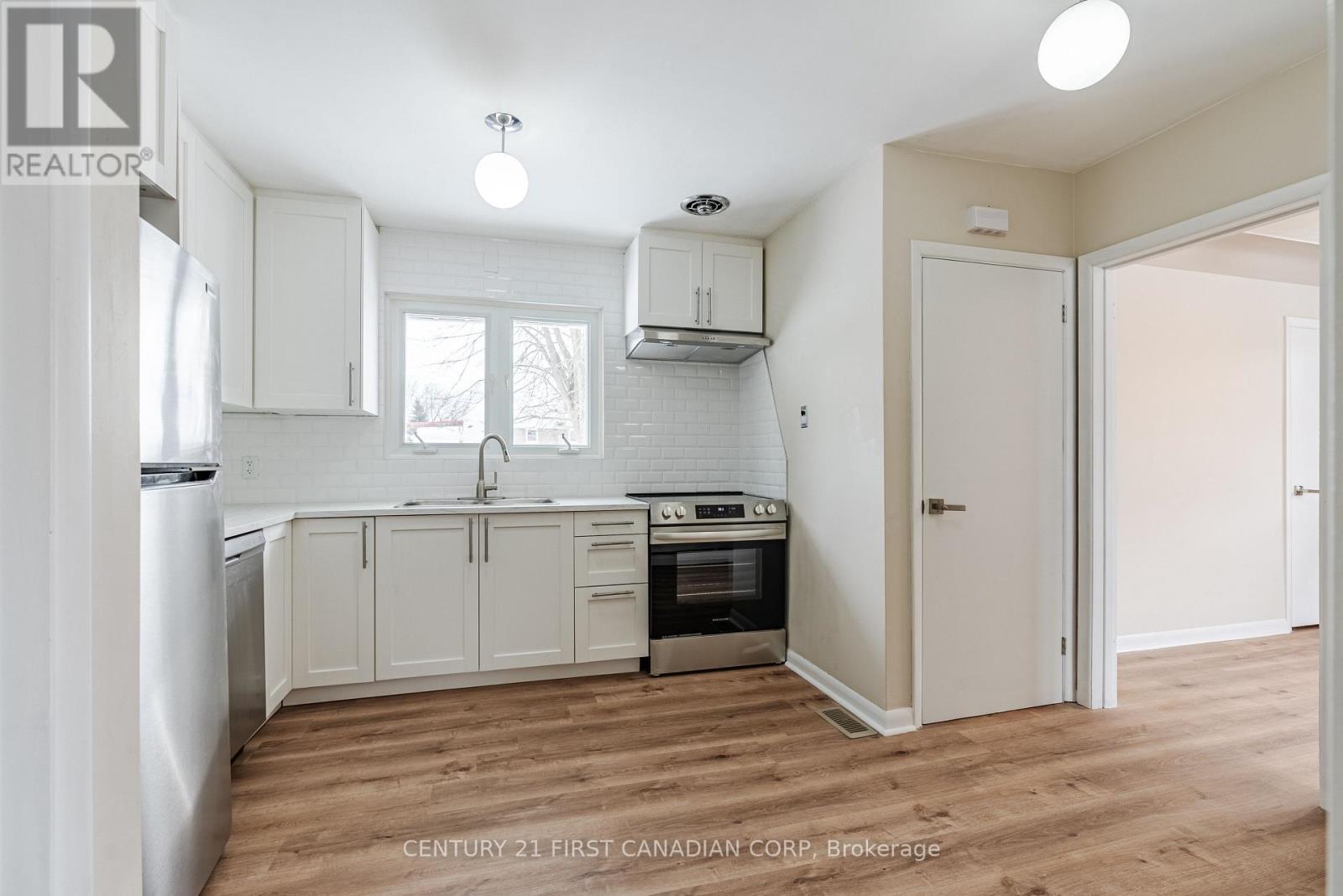 A kitchen with white cabinets and a wooden floor.