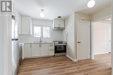 A kitchen with white cabinets and a wooden floor.