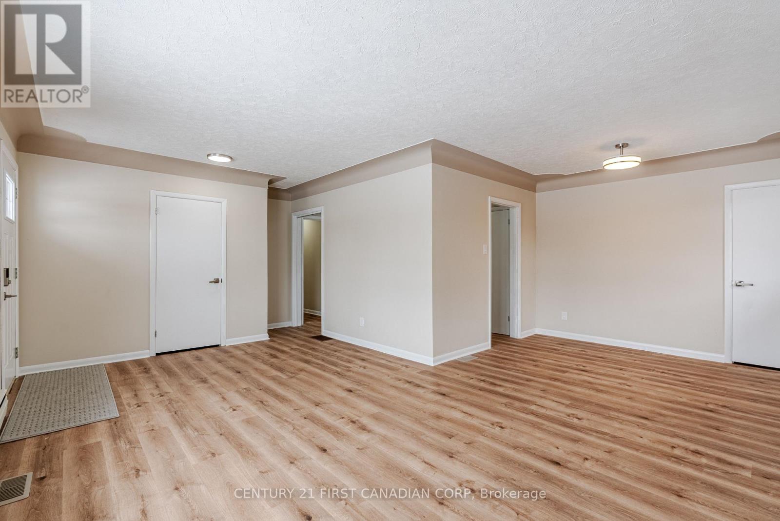 A spacious room with wooden flooring and white walls.