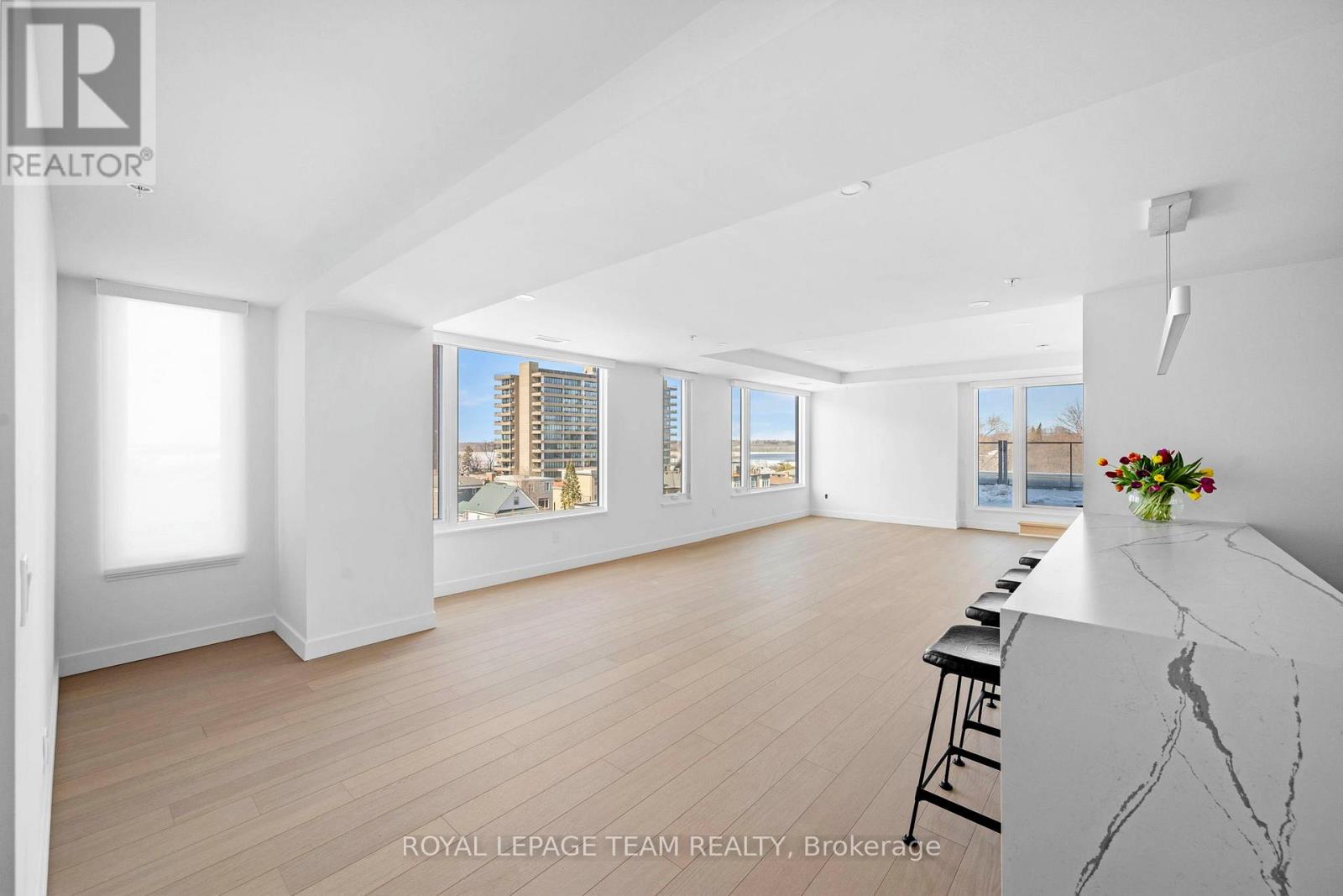 A spacious, well-lit room with a bar area and a view of a cityscape through the windows.