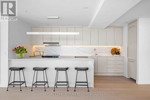 A modern kitchen with white cabinets and a central island with a breakfast bar.