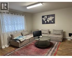 A living room with a couch, a coffee table, and a television.