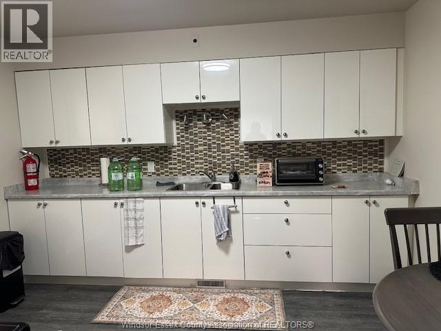 A kitchen with white cabinets and a patterned backsplash.