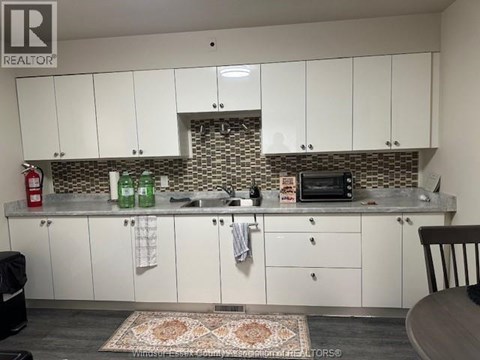 A kitchen with white cabinets and a patterned backsplash.